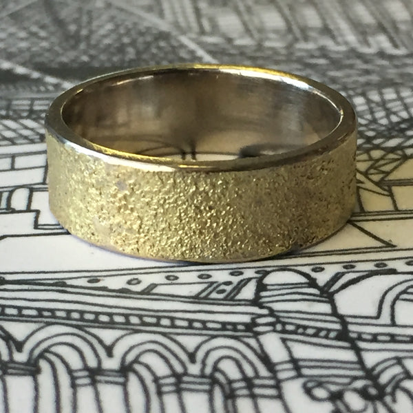 Golden Earth 7mm wedding ring by Jeanette Dyke. Handcrafted in 9ct rose gold with 9ct white gold frosting and black diamonds, showcasing earthy textures.