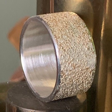 Golden Earth wide wedding ring by Jeanette Dyke. Handcrafted in sterling silver with 18ct rose gold, featuring a bold, textured design and black diamonds.