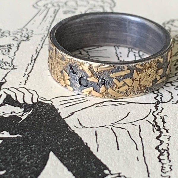 Golden Earth wedding ring by Jeanette Dyke. Handcrafted in sterling silver with 18ct yellow gold and black diamonds, featuring textured detailing for a unique design.