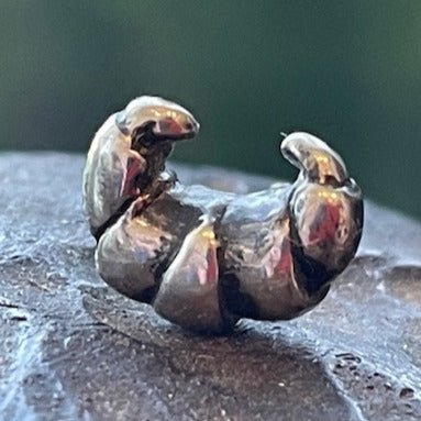Croissant lapel pin by Victoria Mason. Handcrafted in sterling silver, featuring a detailed croissant design for a whimsical, stylish accessory.
